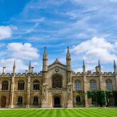 A grand university building with spires and arched windows under a blue, cloudy sky. This scene might inspire questions about how long does a business degree take to complete.