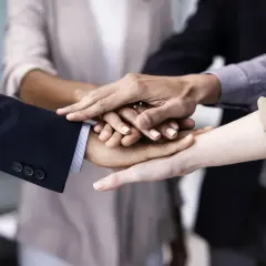 A diverse group of people stack their hands, symbolizing unity and teamwork. This image shows why is respect important for building strong connections.