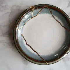A broken plate repaired with gold, symbolizing how long does it take to rebuild trust. The cracks are highlighted, making the repair a feature.