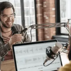 Two people recording internal company podcasts, with microphones and headphones.
