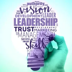 A hand draws a lightbulb filled with words like "Leadership," "Vision," and "Skill," symbolizing effective leadership branding.