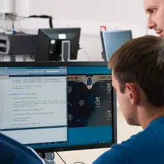 Students learn computer information systems online, coding and playing a space game on a dual-monitor setup.