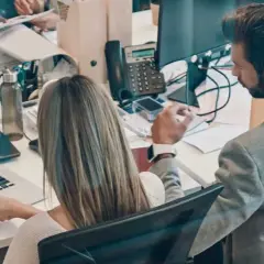Colleagues analyze sales data on a laptop, a scene that could be part of an online business intelligence degree program.