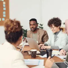 A diverse team collaborates, showcasing high employee engagement and motivation as they brainstorm ideas around a table with laptops and notes.