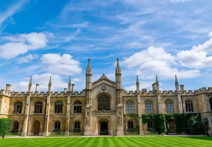 A grand university building with spires and arched windows under a blue, cloudy sky. This scene might inspire questions about how long does a business degree take to complete.