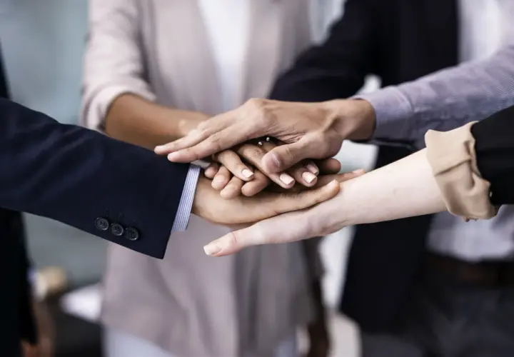 A diverse group of people stack their hands, symbolizing unity and teamwork. This image shows why is respect important for building strong connections.