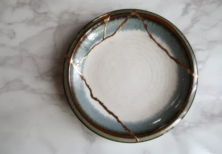 A broken plate repaired with gold, symbolizing how long does it take to rebuild trust. The cracks are highlighted, making the repair a feature.