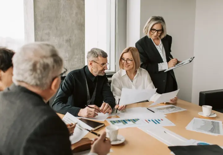 A diverse team collaborates on charts and documents, showcasing effective leadership in a hybrid work environment.