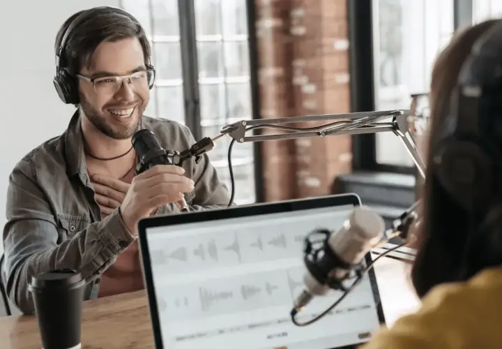 Two people recording internal company podcasts, with microphones and headphones.