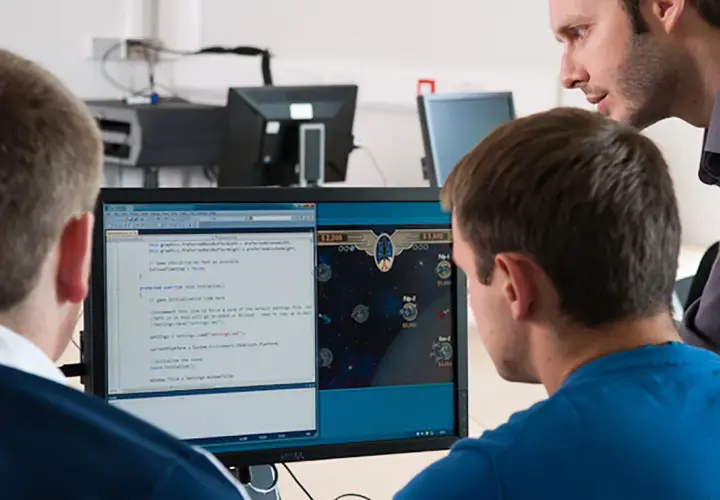 Students learn computer information systems online, coding and playing a space game on a dual-monitor setup.
