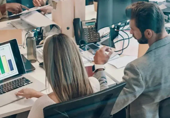 Colleagues analyze sales data on a laptop, a scene that could be part of an online business intelligence degree program.