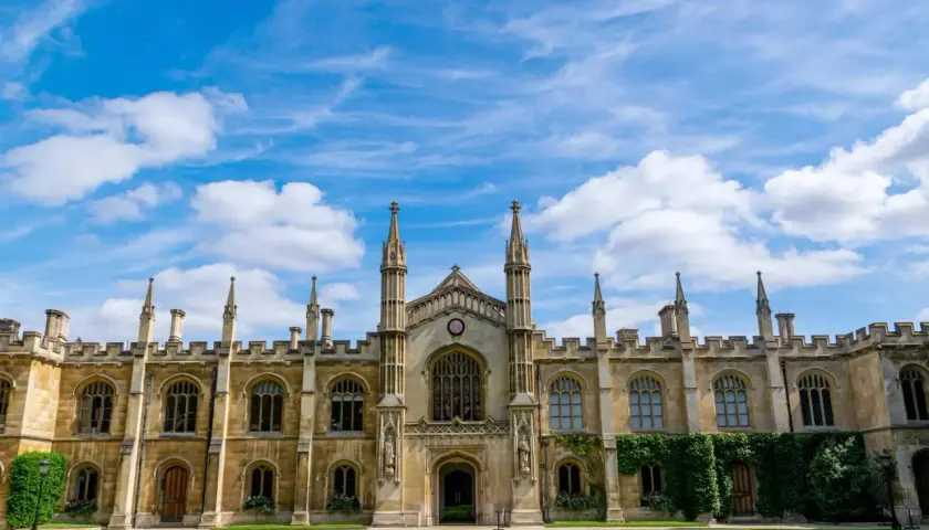 A grand university building with spires and arched windows under a blue, cloudy sky. This scene might inspire questions about how long does a business degree take to complete.