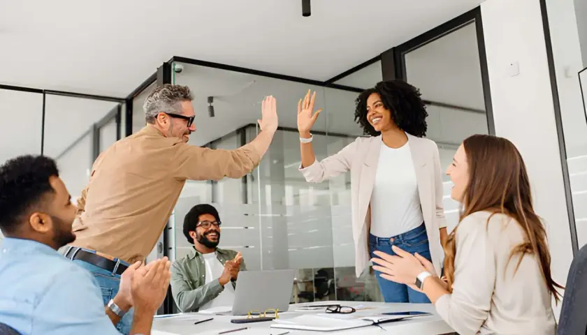 Team celebrates success after a leadership communication training session. High-fives and smiles abound as they master new skills.