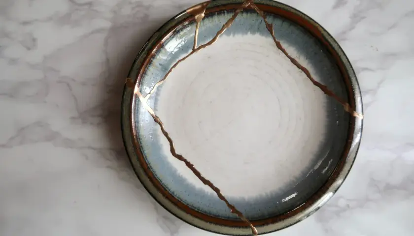 A broken plate repaired with gold, symbolizing how long does it take to rebuild trust. The cracks are highlighted, making the repair a feature.