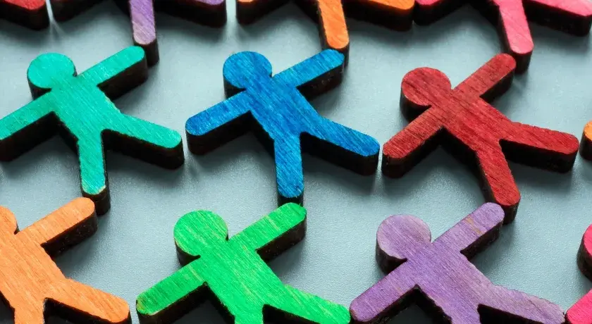 Colorful wooden figures represent a diverse community, highlighting the importance of EDI (Equity, Diversity, Inclusion) over DEI (Diversity, Equity, Inclusion).