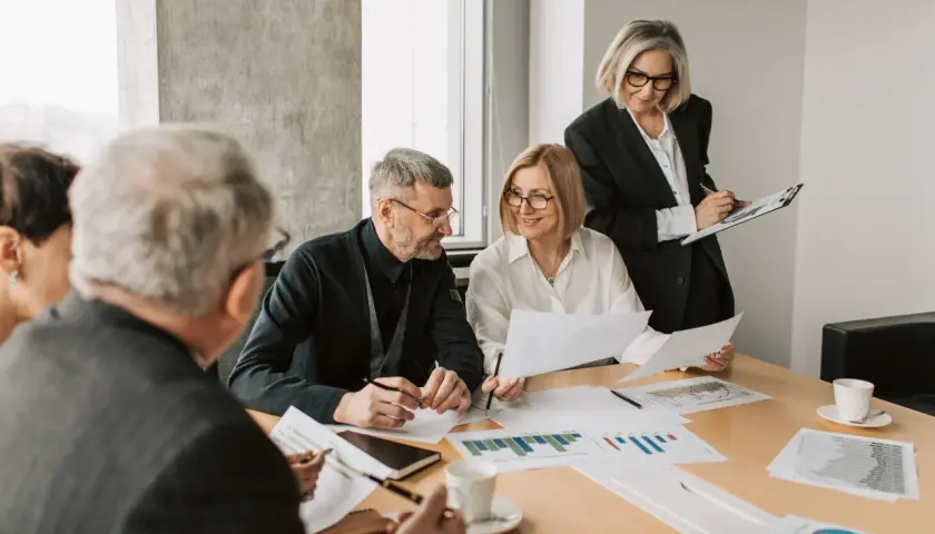 A diverse team collaborates on charts and documents, showcasing effective leadership in a hybrid work environment.