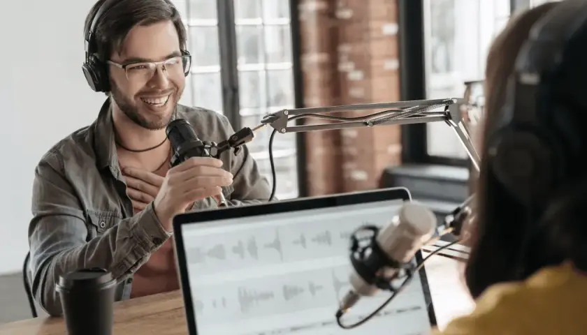 Two people recording internal company podcasts, with microphones and headphones.