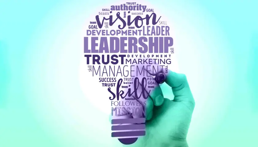 A hand draws a lightbulb filled with words like "Leadership," "Vision," and "Skill," symbolizing effective leadership branding.