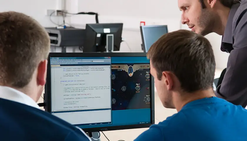 Students learn computer information systems online, coding and playing a space game on a dual-monitor setup.