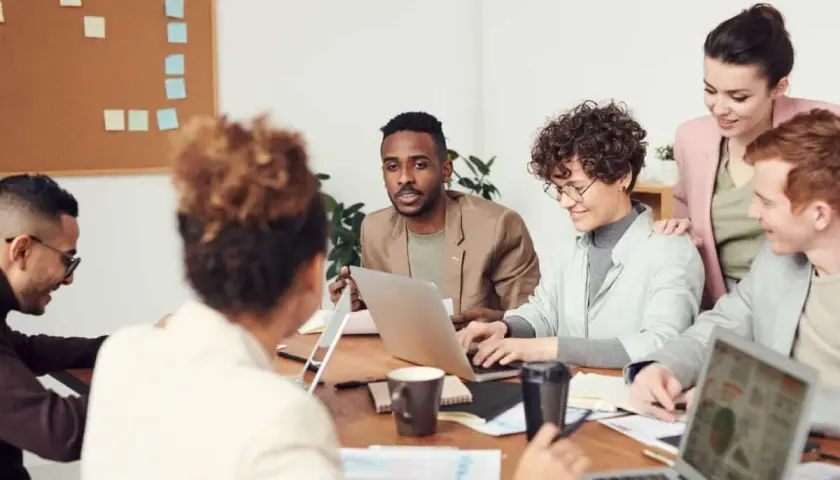A diverse team collaborates, showcasing high employee engagement and motivation as they brainstorm ideas around a table with laptops and notes.