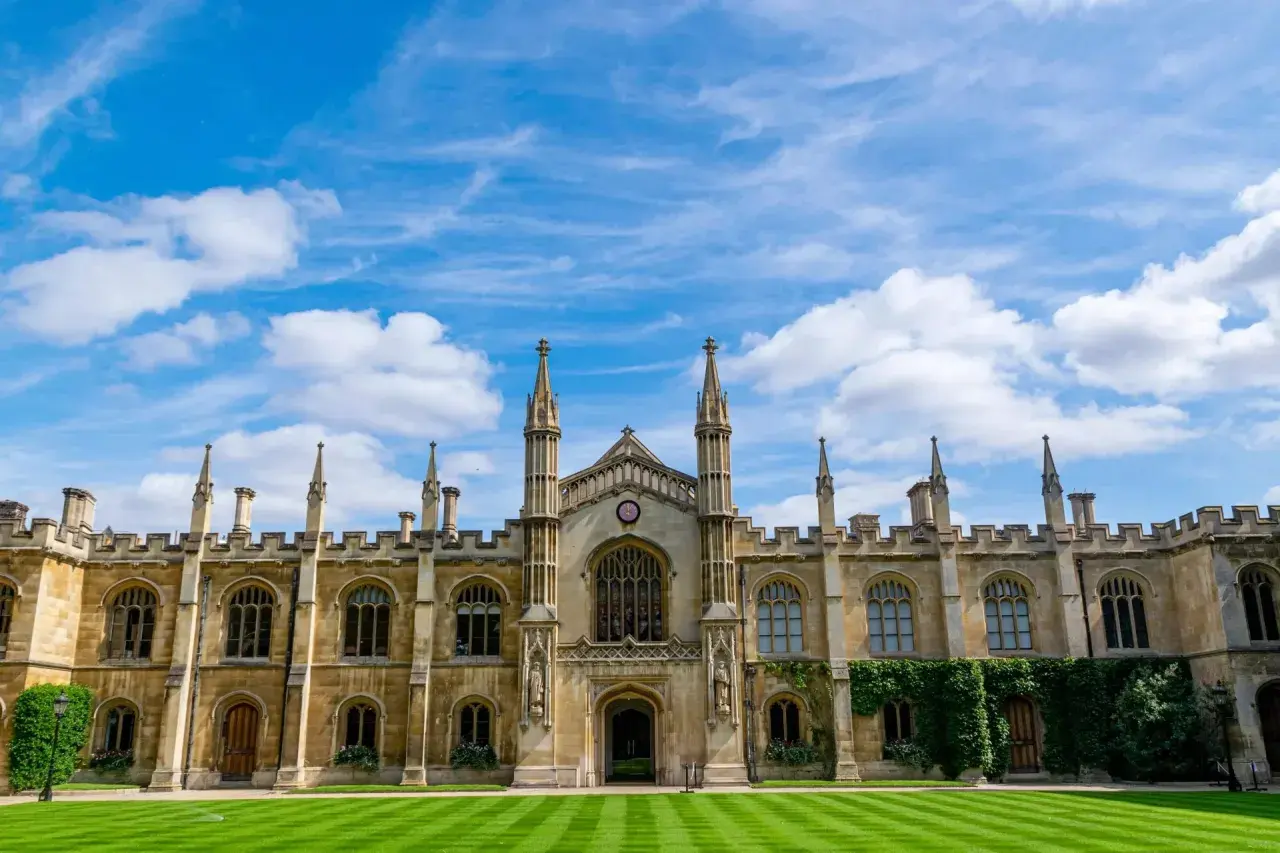 A grand university building with spires and arched windows under a blue, cloudy sky. This scene might inspire questions about how long does a business degree take to complete.