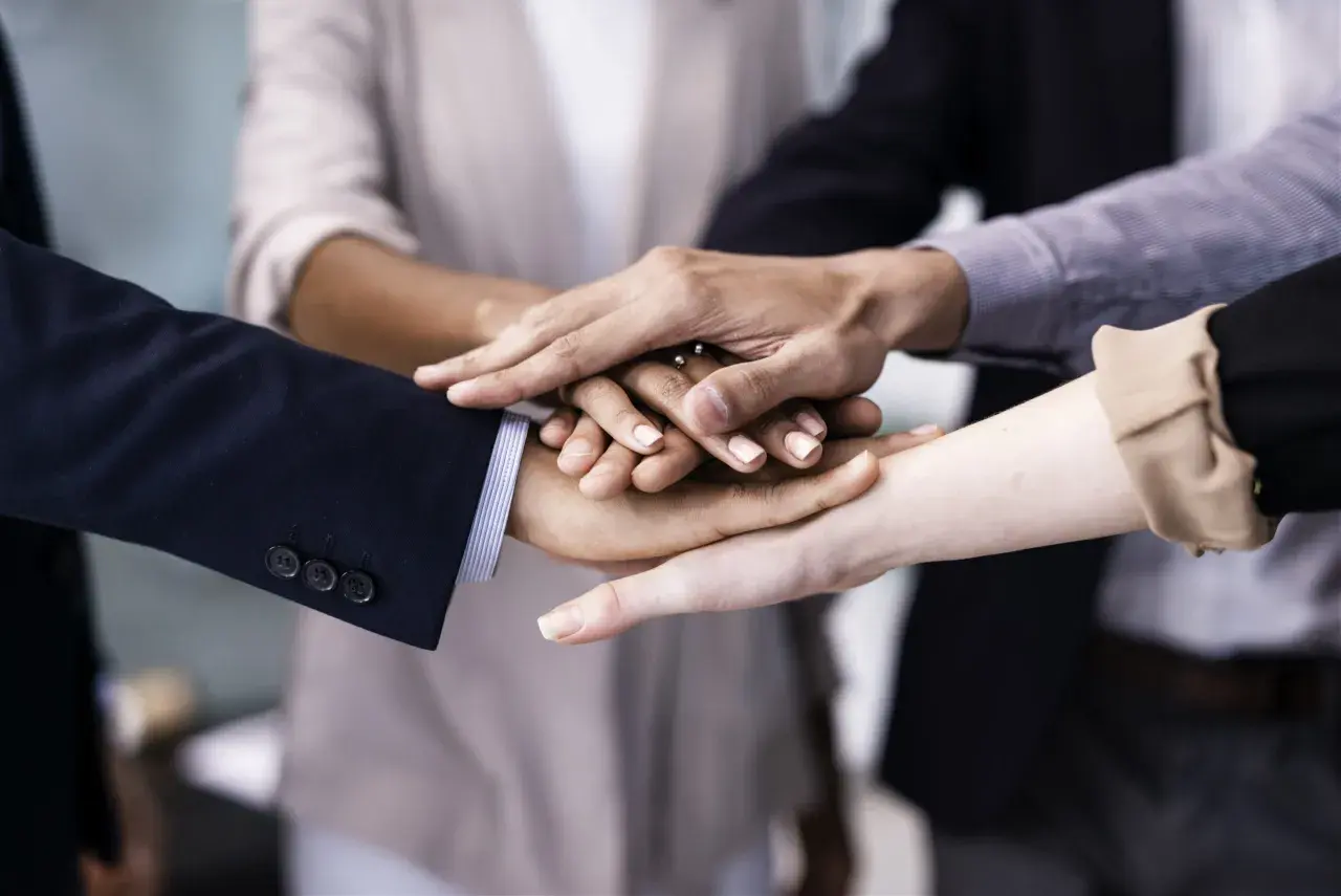 A diverse group of people stack their hands, symbolizing unity and teamwork. This image shows why is respect important for building strong connections.