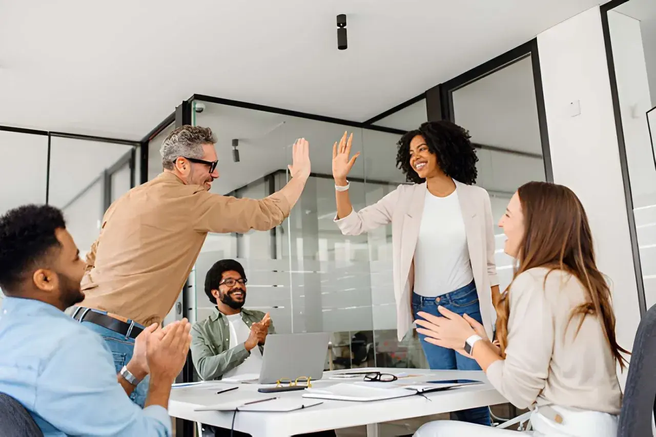 Team celebrates success after a leadership communication training session. High-fives and smiles abound as they master new skills.