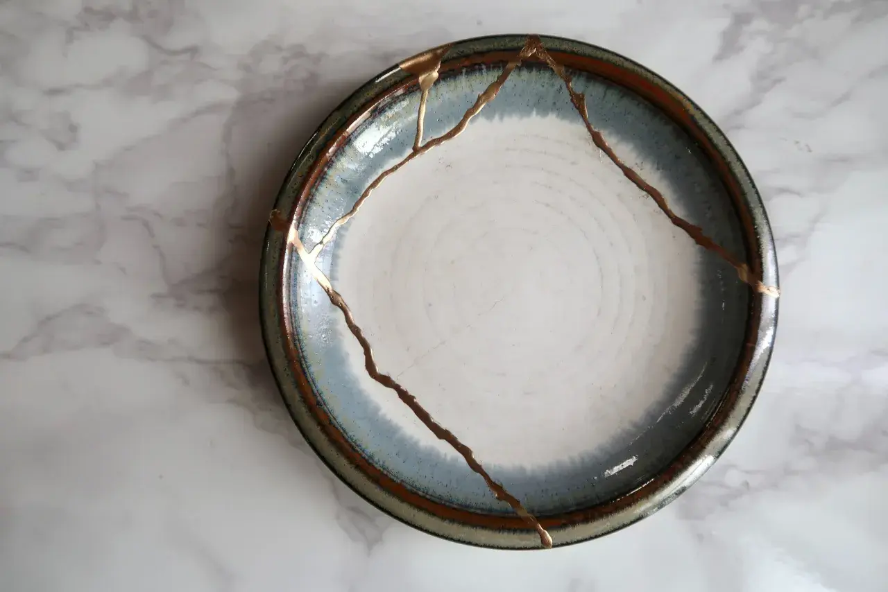 A broken plate repaired with gold, symbolizing how long does it take to rebuild trust. The cracks are highlighted, making the repair a feature.