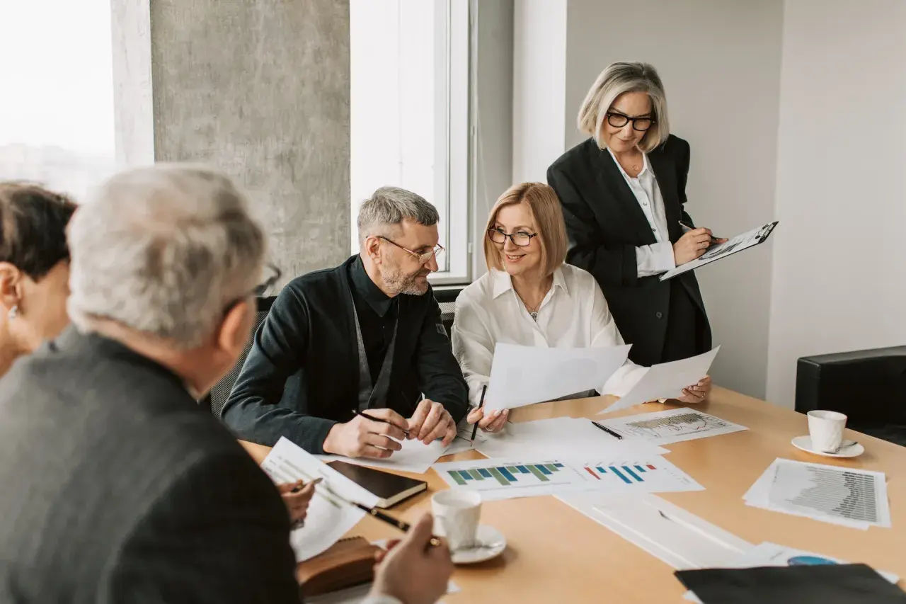 A diverse team collaborates on charts and documents, showcasing effective leadership in a hybrid work environment.