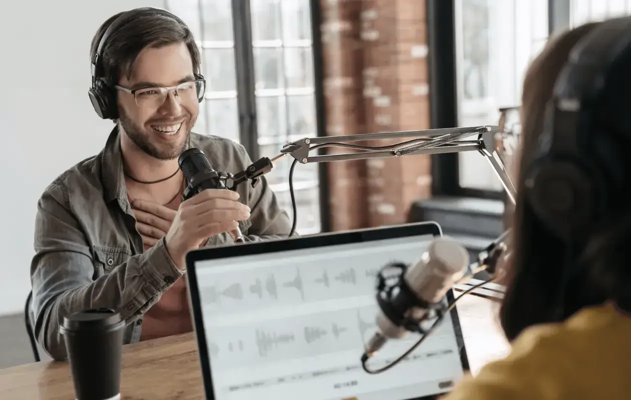 Two people recording internal company podcasts, with microphones and headphones.