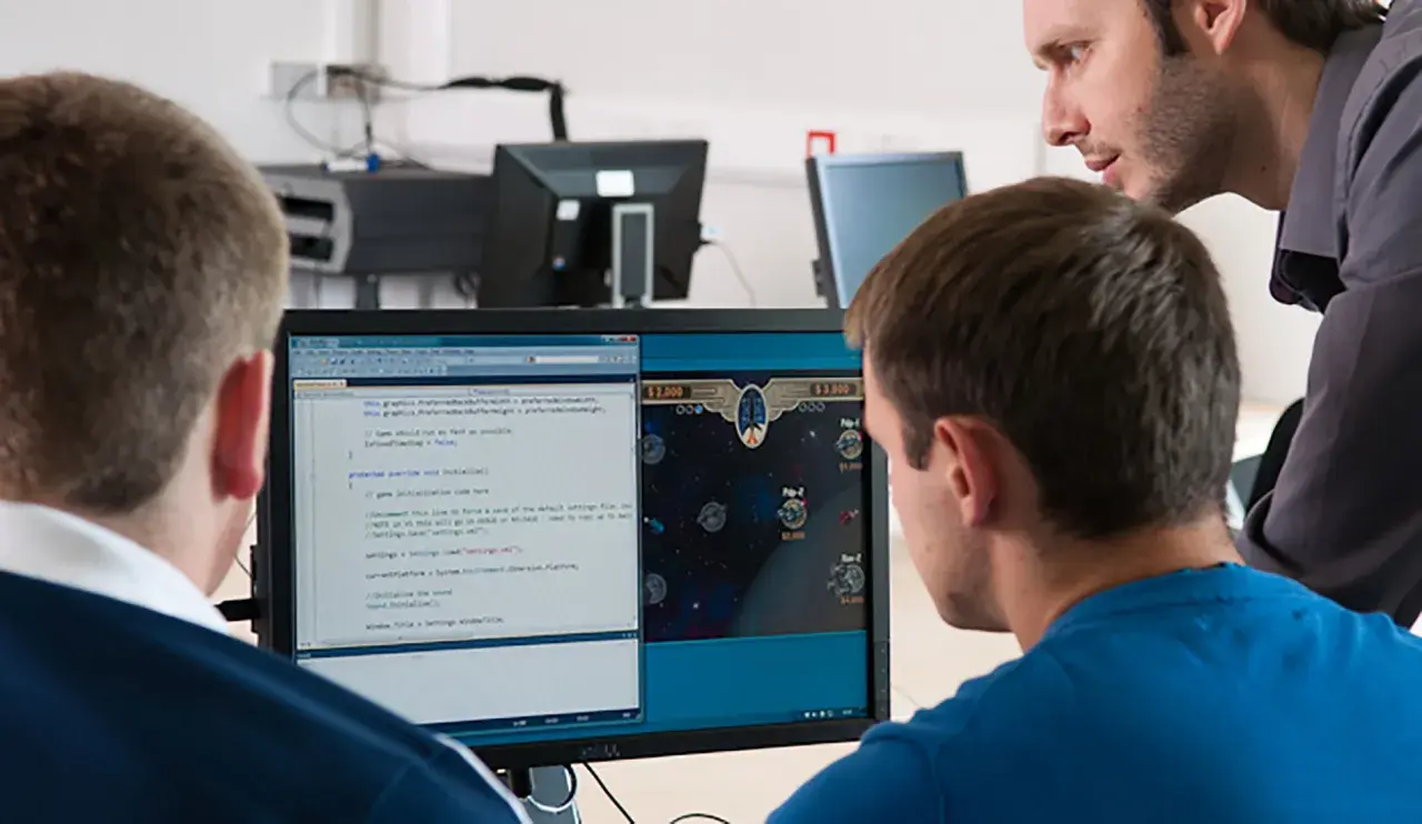 Students learn computer information systems online, coding and playing a space game on a dual-monitor setup.