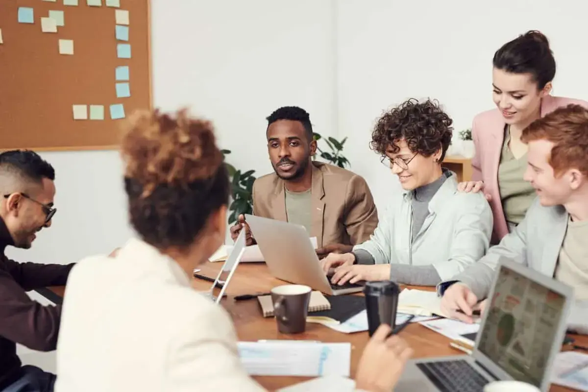 A diverse team collaborates, showcasing high employee engagement and motivation as they brainstorm ideas around a table with laptops and notes.