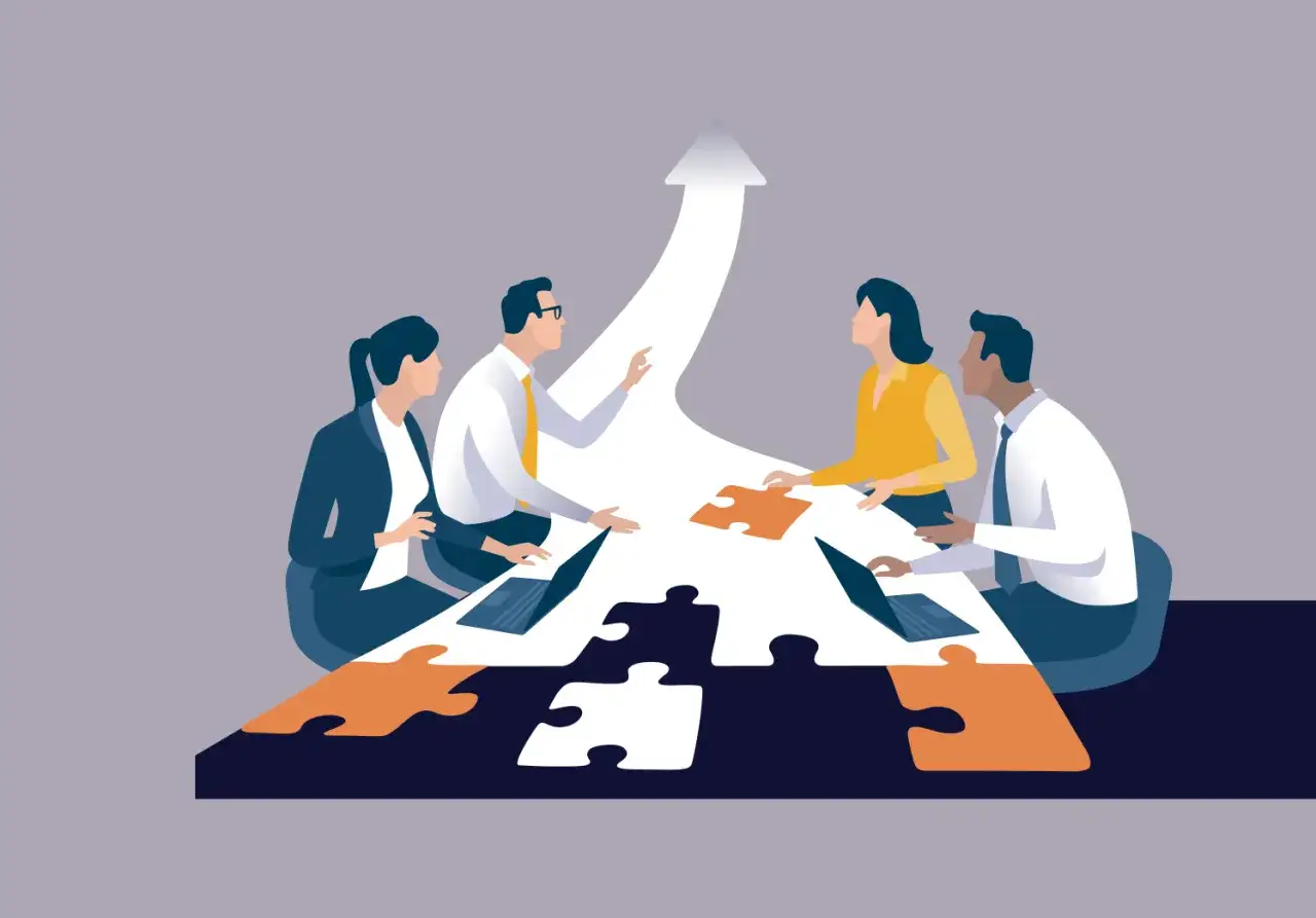 Team members collaborate around a puzzle-shaped table, symbolizing leadership alignment and a shared path forward.