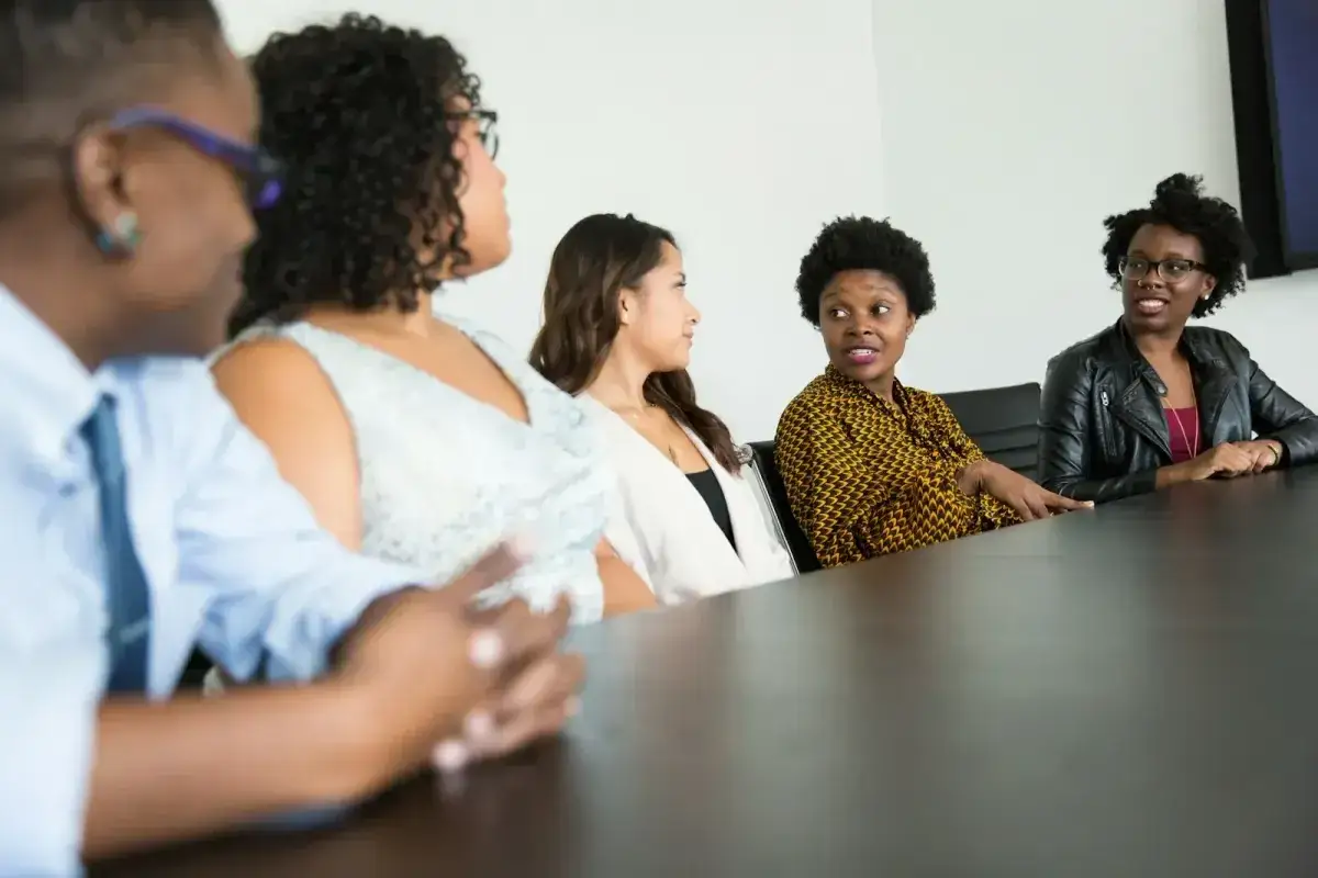 Diverse women in a meeting, discussing ideas and reframing leadership.