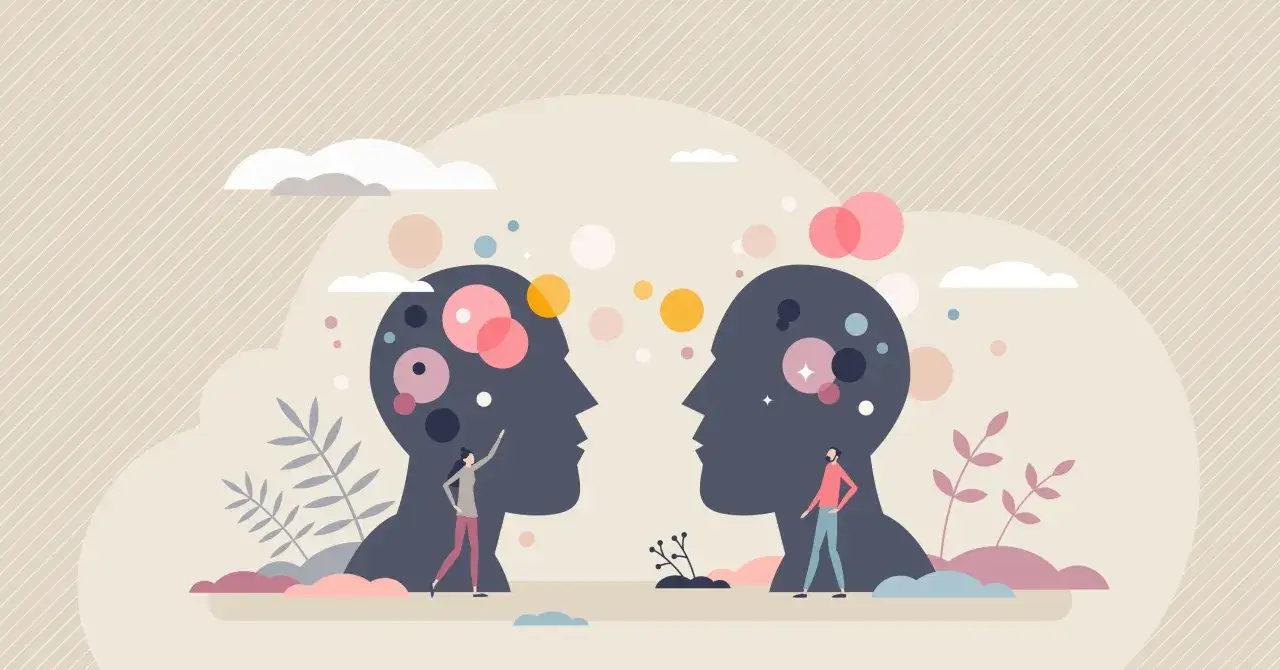 Two silhouettes of heads face each other, with small figures interacting with colorful circles inside. This illustrates the difference between compassion and empathy.