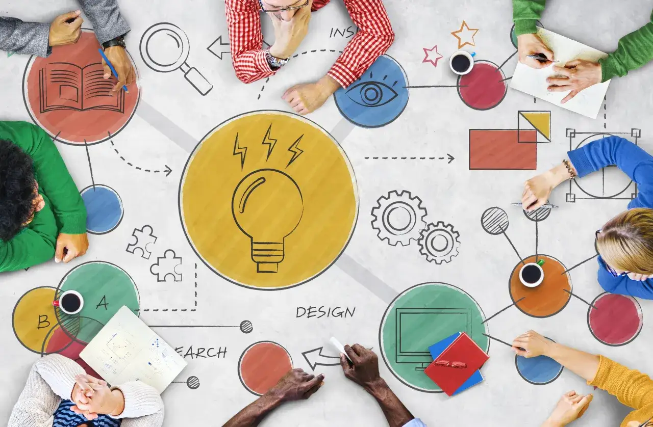 A team collaborates on a group charter, brainstorming ideas with a lightbulb, eye, and gears, symbolizing research, design, and innovation.