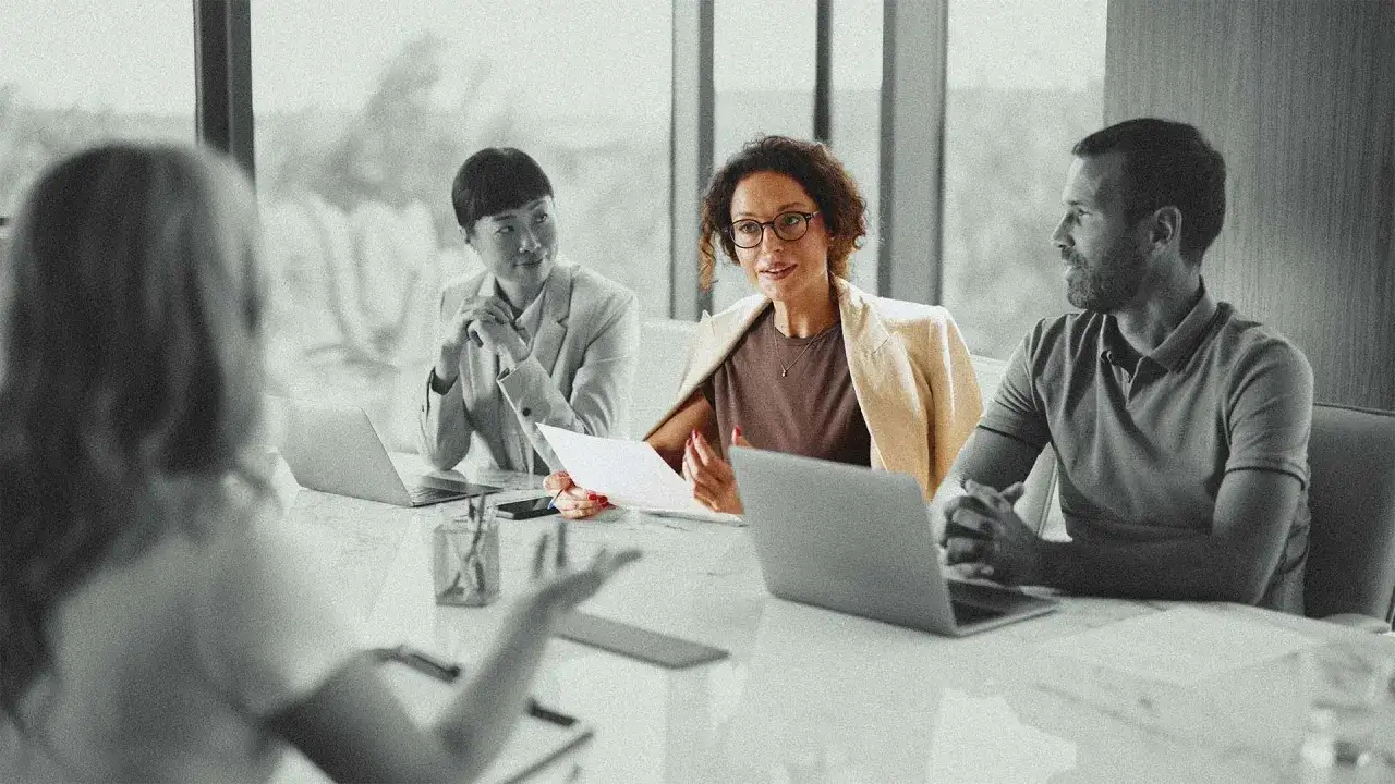 Diverse team in a meeting, discussing documents. This scene illustrates leadership accountability examples through collaborative problem-solving.