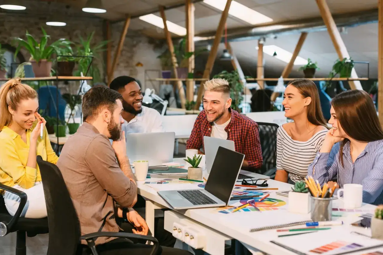 A diverse team collaborates, their laughter suggesting that accountability can feel like an attack, but here it's a shared, positive experience.