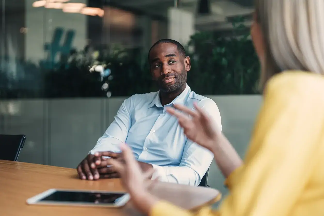 A man in a light blue shirt listens intently, embodying authentic leadership during a meeting.