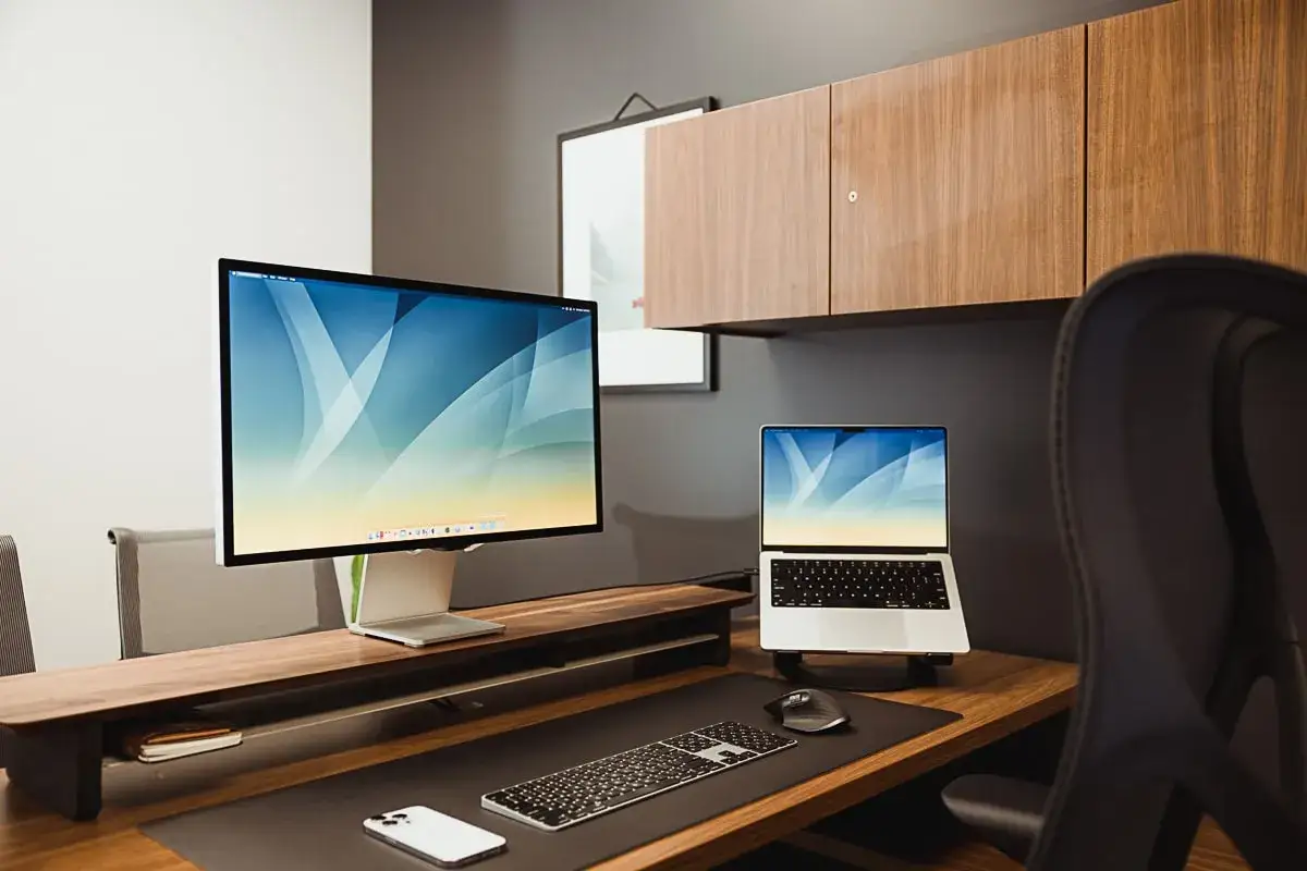 A clean desk setup with a large monitor and laptop, perfect for learning how to focus at work.