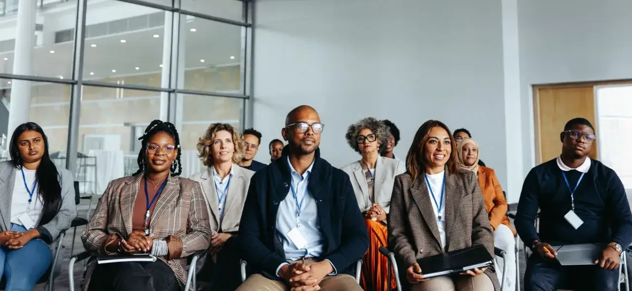 A diverse group of professionals attends a meeting, showcasing inclusive language in the workplace.