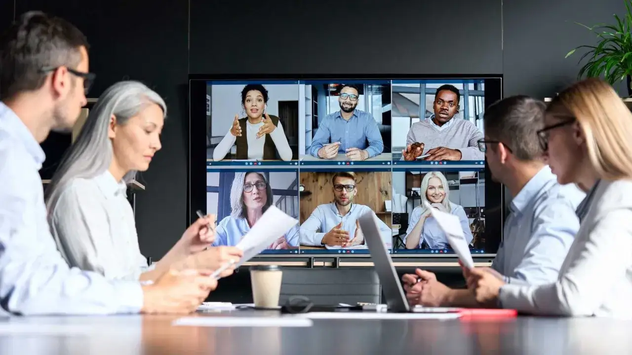 Team members collaborate on a video call, showcasing effective communication for leading in a hybrid work environment.