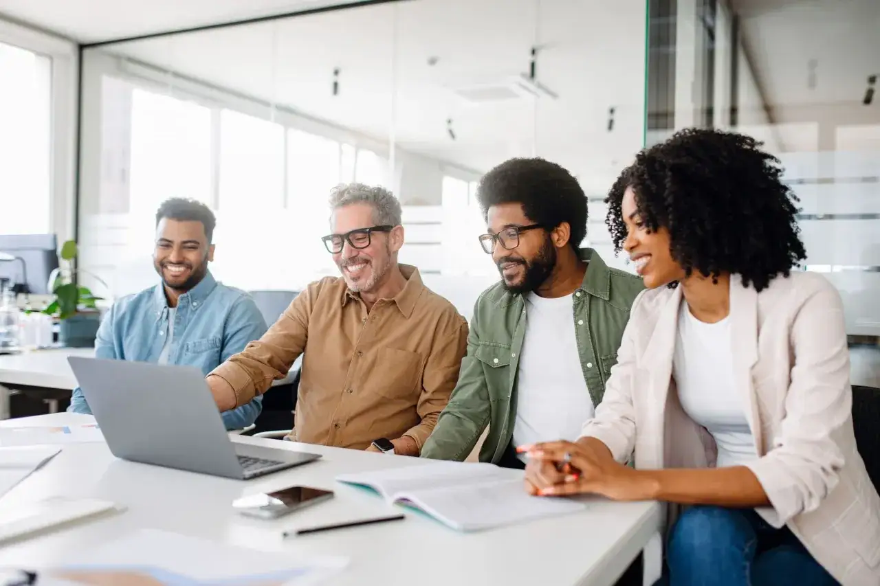 A diverse team collaborates, increasing employee motivation as they review a laptop.