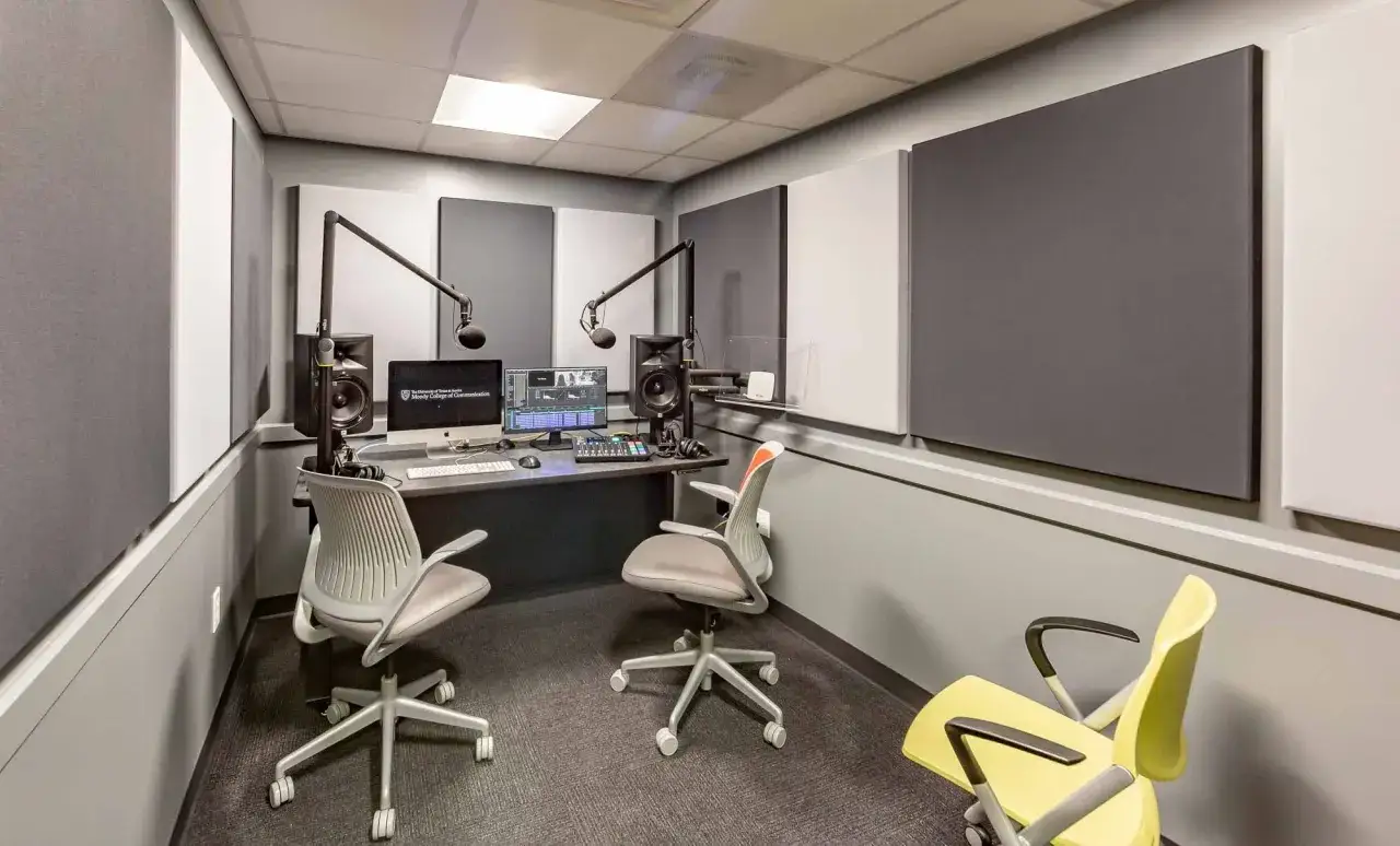 A sound-treated room with microphones, monitors, and chairs, ready for recording an internal communications podcast.