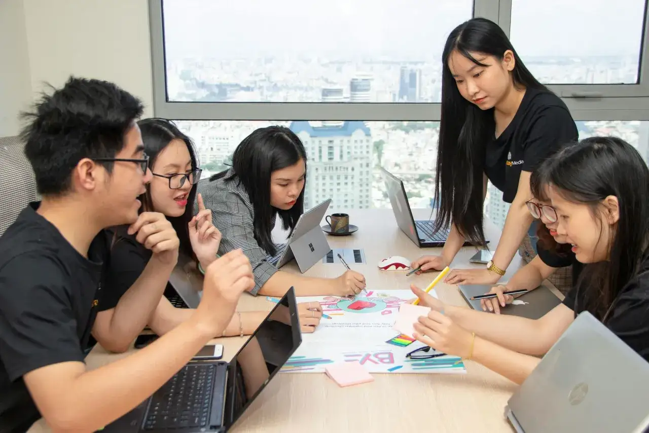 A diverse team collaborates on an internal communication strategy, brainstorming ideas around a table with laptops and colorful notes.