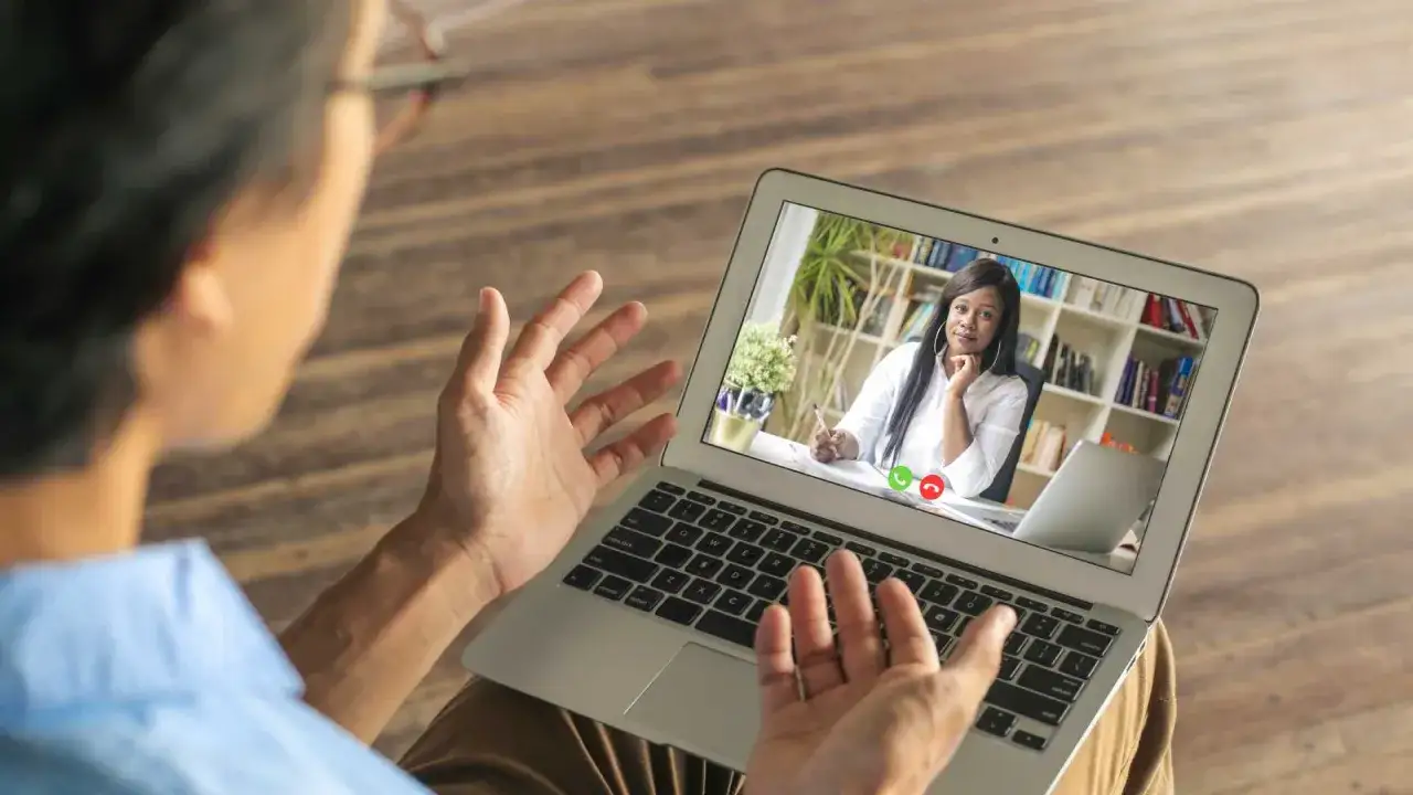 A man engages in virtual leadership development via a video call with a woman who is coaching him.