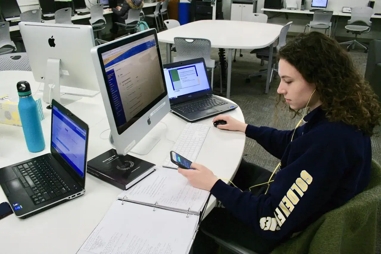 A student studies for online undergraduate certificate programs, surrounded by multiple screens and notes.