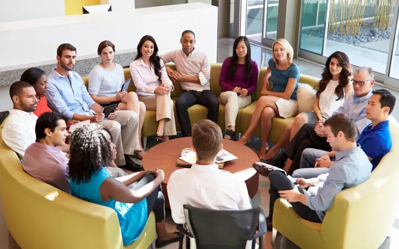 A diverse group of people sit in a circle, discussing ideas. This scene embodies the erg meaning of collaboration and shared purpose.