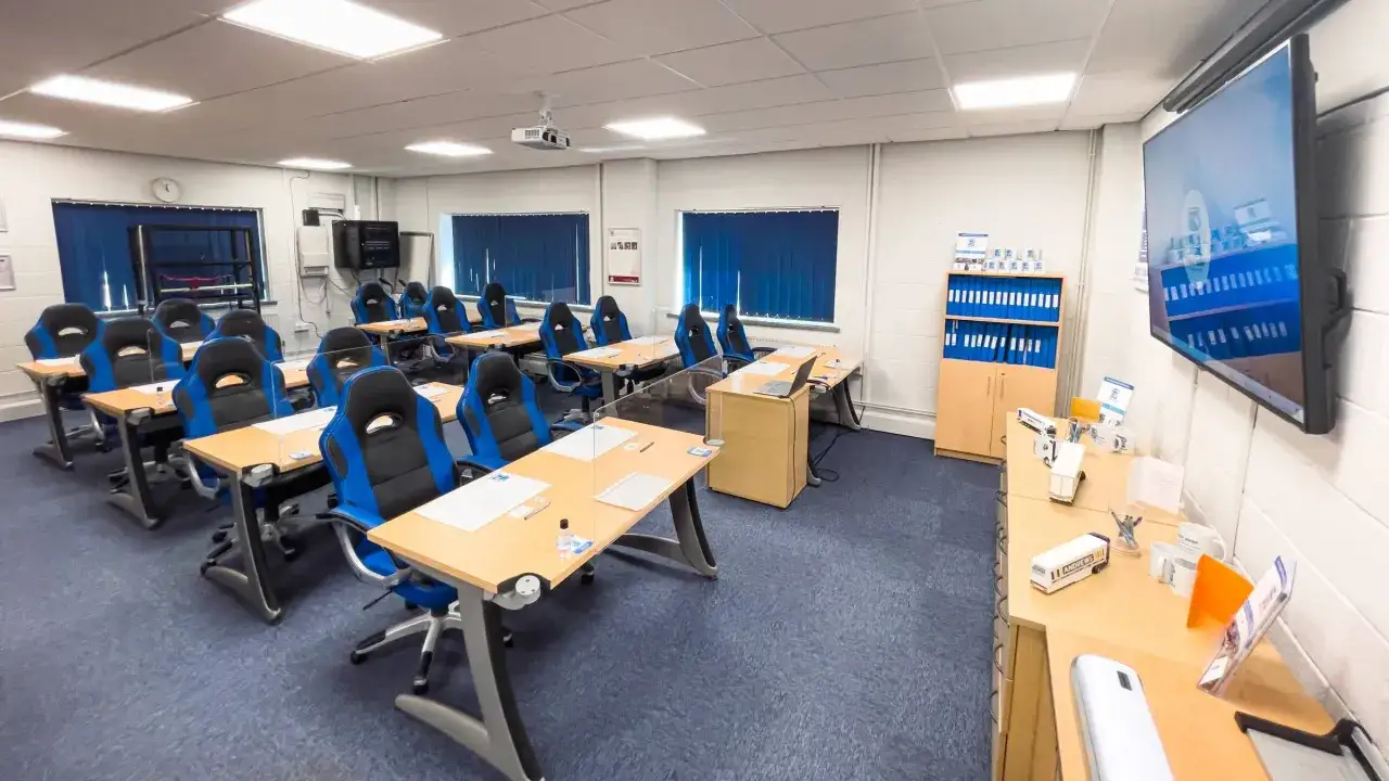 Classroom with blue and black racing chairs, desks, and a projector. This space is ideal for learning about CPC certification cost and other professional development.