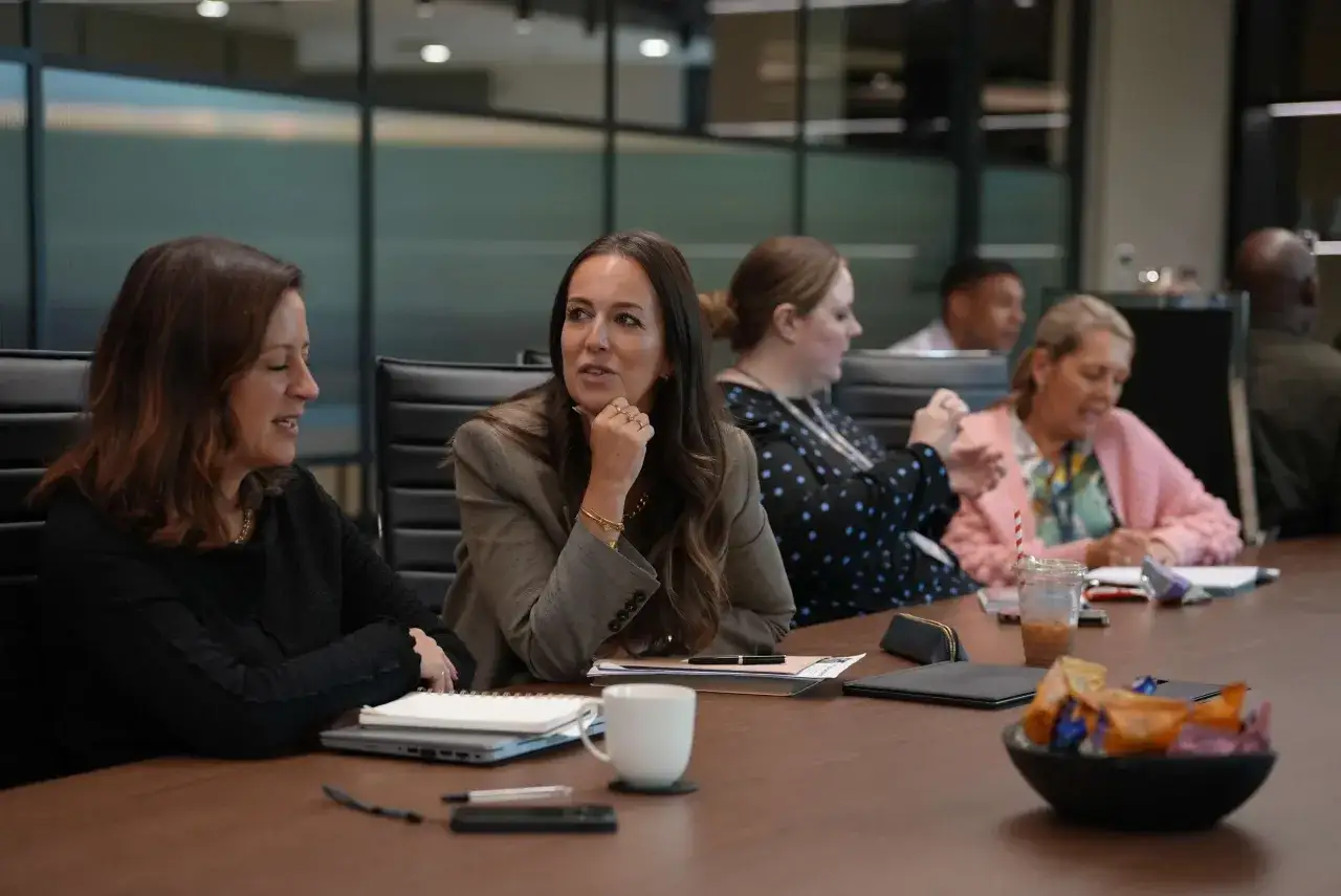 Attendees engage in a lively discussion during a communication workshop, sharing ideas and insights around a conference table.
